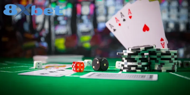 Bộ bài với bốn lá Át, xúc xắc và chồng phỉnh trên bàn nỉ xanh, logo 8Xbet ở góc trái