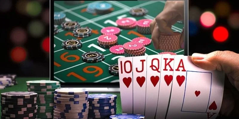 Tay cầm bộ bài cùng chồng chip trước màn hình bàn roulette trực tuyến, minh họa sự kiện 8xbet